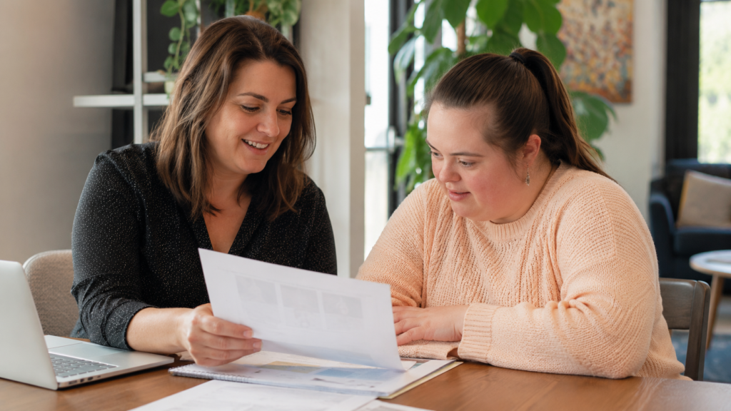 A support coordinator and an NDIS participant reviewing a plan together at a table